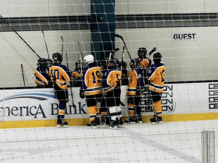 Photograph taken by Ellea Kersey: Oakland Tech Ice Hockey has a team huddle during a game.